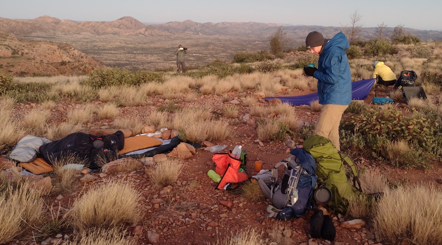 Phil enjoying a warming brew of coffee while Fraser packed, and Elise documented. My camp site at left.'